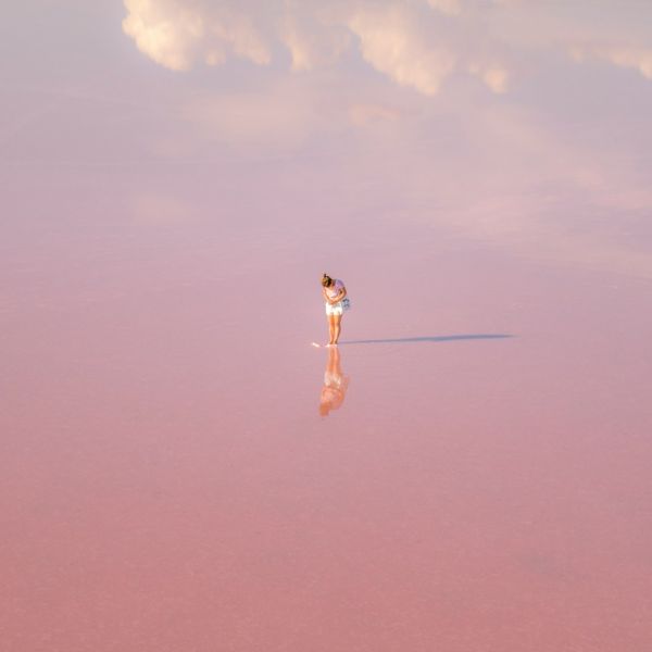 woman in white dress standing on brown sand under blue sky during daytime